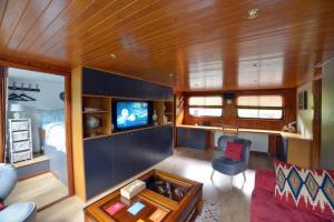 sala de estar con sofá y TV en Péniche Rayclau, en Ronquières