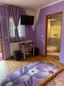 a bedroom with purple walls and a table with a rug at Pensiunea Ioana Mariana in Botiza