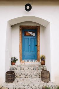 una puerta azul en una casa blanca con dos barriles en La Victorel, en Porumbacu de Sus