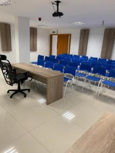 una sala de conferencias con una mesa de madera y sillas azules en San Lucas Hotel, en Sarandi