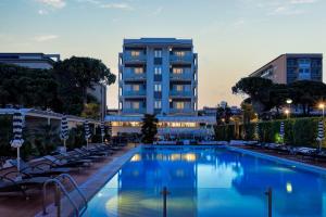 une piscine avec des chaises et un bâtiment en arrière-plan dans l'établissement Hotel Delle Rose, à Lido di Jesolo