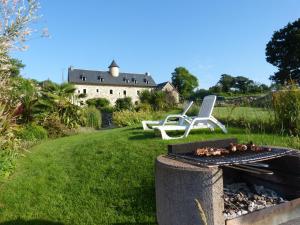 a grill with a chair and a house in the background at GITE DE CARACTERE in Lopérec