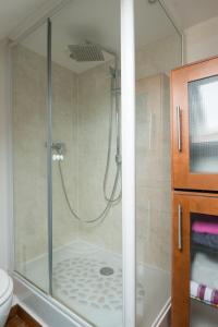 La salle de bains est pourvue d'une douche avec une porte en verre. dans l'établissement Le Teck, à Deauville