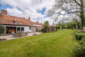 a garden with a patio and a house at Lavender Cottage in Saxmundham