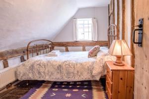 a bedroom with a bed and a lamp on a table at Lavender Cottage in Saxmundham