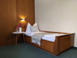 Una cama en una habitación con una mesa con flores. en Hotel Schönbrunn, en Merano