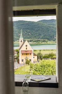 una ventana con vistas a una iglesia y a un lago en Apartments Seewinkel en Caldaro