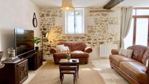 uma sala de estar com mobiliário de couro e uma televisão em La Châtaigne em Piégut-Pluviers