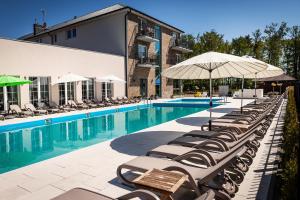 a pool with chairs and umbrellas next to a building at Dom Wczasowy Kliper in Niechorze