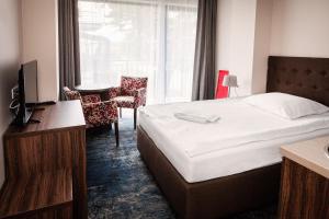a hotel room with a bed and a tv and a window at Dom Wczasowy Kliper in Niechorze