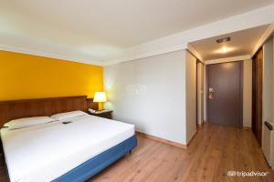 a bedroom with a white bed and a yellow wall at Rede Andrade Braz in Curitiba