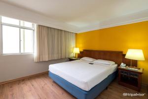 a bedroom with a large bed and a yellow wall at Rede Andrade Braz in Curitiba