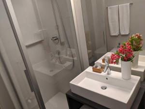 a white bathroom with a sink and a shower at Hotel Schönbrunn in Merano