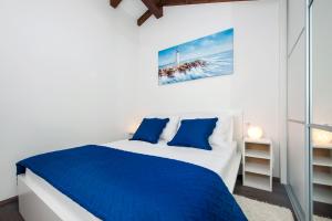 białe łóżko z niebieskimi poduszkami w sypialni w obiekcie The Attic Rovinj w Rovinj