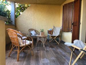 een veranda met rieten stoelen en een tafel en stoelen bij CASA LA TANCA in Isola Rossa