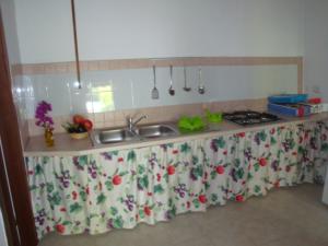 a kitchen counter with a sink with a flowered curtain at Sunset Lodge in Paola