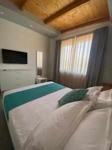 a bedroom with a large white bed with a television at La Via del Mare in Licola