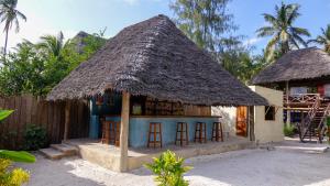 a small house with stools and a thatched roof at Paje Beach Bandas in Paje