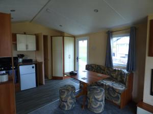 a living room with a table and a couch and a kitchen at Weeley Lakeview Caravan. in Weeley