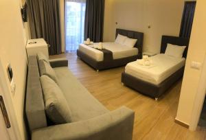 クサミルにあるHotel Adriatik Ksamilのリビングルーム(ベッド2台、ソファ付)