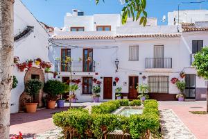 a white house with plants and flowers in front of it at Casa Del Patio - Boutique Apartments in Estepona