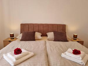 two red roses sitting on towels on a bed at Apartman Tea in Privlaka