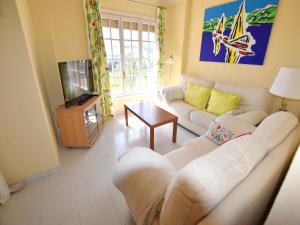 ein Wohnzimmer mit einem weißen Sofa und einem TV in der Unterkunft Apartamento la Isla Javea - 5008 in Jávea