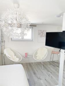 uma sala de estar com uma televisão e uma mesa e cadeiras em Appartement Blanc cocooning em Sprimont