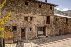 un antiguo edificio de piedra con puertas y ventanas de madera en Casa Mora Vall Fosca en Central