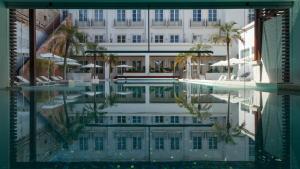 a swimming pool in front of a building with palm trees at Alentejo Marmòris Hotel & Spa, a Small Luxury Hotel of the World in Vila Viçosa