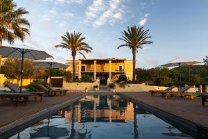 einem Pool mit Stühlen und Sonnenschirmen vor einem Gebäude in der Unterkunft LAS MARIPOSAS in Sant Antoni de Portmany