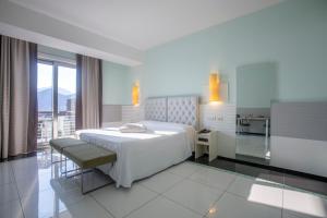 a white bedroom with a bed and a kitchen at Grand Hotel Salerno in Salerno