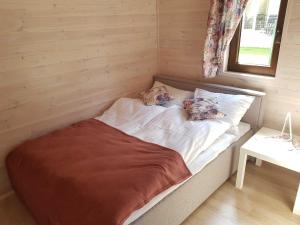 a bed in a wooden room with two pillows on it at Domki Niezapominajka Ustka in Ustka