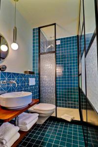 a blue tiled bathroom with a toilet and a shower at Le Tonnelier in Bulle