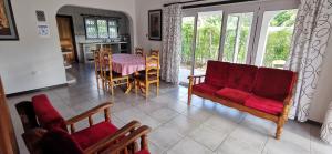 een woonkamer met een rode bank en een tafel bij CHEZ MARVA Grande Villa Corossol 3 à 12 personnes in La Digue