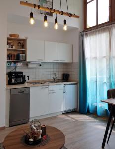 cocina con armarios blancos, mesa y ventana en Ferienwohnung 32 im Ferienland Sonnenwald - Bayerischer Wald, en Schöfweg