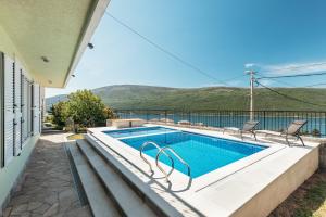 a swimming pool with two chairs next to a house at VILLA ALEXANDRA in Kumbor