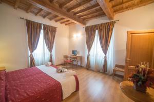 a bedroom with a bed with a table and windows at HG Abetone e Piramidi Resort in Abetone +105 photos