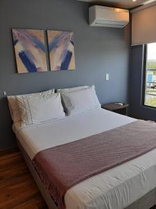 Santorini Apartamentos Amoblados في بيريرا: غرفة نوم بسرير كبير عليها لوحتين