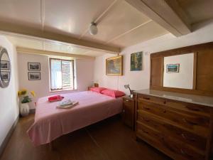 a bedroom with a bed with pink sheets and a dresser at La Casa di Sissy in Trasquera