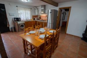 eine Küche mit einem Holztisch mit Stühlen und einem Kühlschrank in der Unterkunft Casa Cuesta del Álamo. Vistas frente Puente Lata in Granada