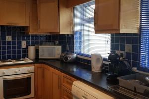 a kitchen with wooden cabinets and a black counter top at Cosy Townhouse on The Hill in Ireland in Banagher