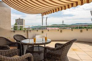 a patio with a table and chairs on a balcony at Pleasure Čair apartments in Niš