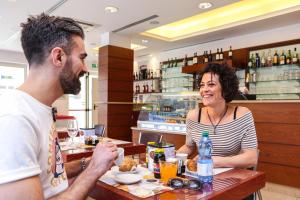 a man and a woman sitting at a table in a restaurant at Wally Residence in Rimini