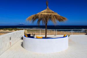 a chair with a straw umbrella on the beach at Villa Island Zembra in El Haouaria