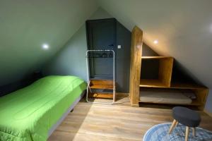 ein Schlafzimmer mit einem grünen Bett im Dachgeschoss in der Unterkunft Agréable chalet Au milieu des sapins in La Plaine des Cafres