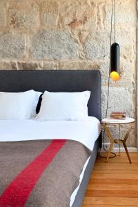 een slaapkamer met een bed en een stenen muur bij Oporto Chic&Cozy - Ribeira in Porto