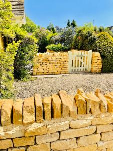 a brick retaining wall with a gate in a yard at Cotswold Chic Retreats "Jacinabox" 5 Star Chipping Campden-Parking-Garden in Chipping Campden