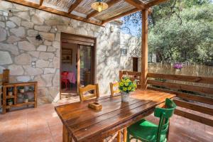 a wooden table on a patio with a stone wall at Villa Olga in Pefkari