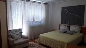 a bedroom with a bed and a chair and a window at Apartman Oasis 2 Ilidza in Sarajevo